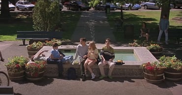 A screenshot from the opening scene of Scream, showing a group of friends hanging out by a fountain in the town square.